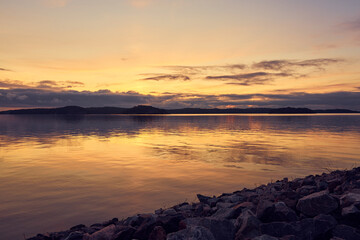A colofrul sunset with reflections on water and granite stones on a foreground in an archipelago in Parainen, Finland.