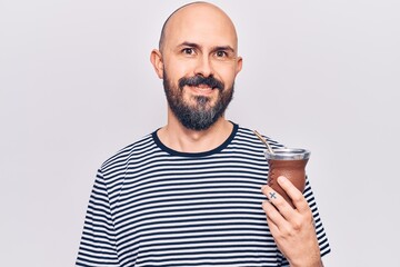 Young handsome man drinking mate infusion looking positive and happy standing and smiling with a confident smile showing teeth