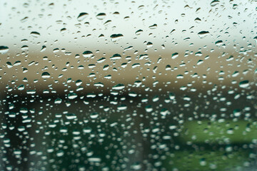 Rain drops on a glass window as an abstract blurred background. Selective focus.