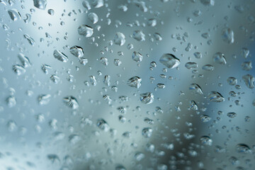 Rain drops on a glass window as an abstract blurred background. Selective focus.