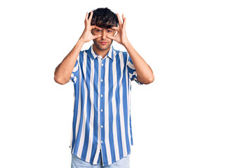 Young hispanic man wearing casual clothes trying to open eyes with fingers, sleepy and tired for...