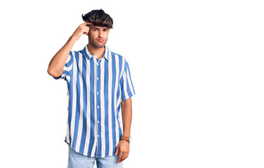 Young hispanic man wearing casual clothes pointing unhappy to pimple on forehead, ugly infection of blackhead. acne and skin problem