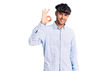 Young hispanic man wearing casual shirt smiling positive doing ok sign with hand and fingers. successful expression.
