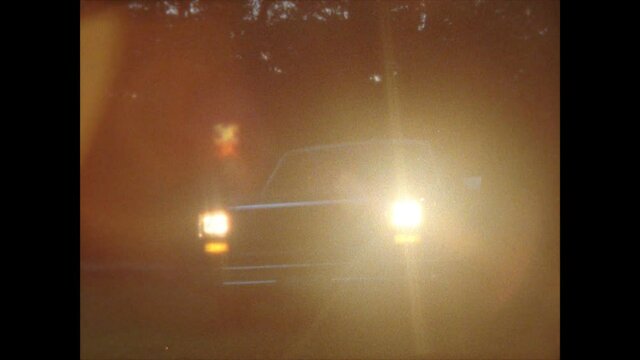 Retro / Vintage / Classic 1970s pickup truck enters frame and shines headlights at camera / shot on Super 8 film
