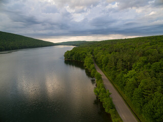 Fototapeta premium Aerial view of road through forest on border of lake