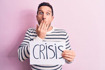 Young handsome man asking for economy holding paper with crisis word message covering mouth with...