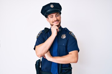 Young caucasian man wearing police uniform looking confident at the camera smiling with crossed arms and hand raised on chin. thinking positive.