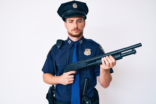 Young caucasian man wearing police uniform holding shotgun depressed and worry for distress, crying angry and afraid. sad expression.