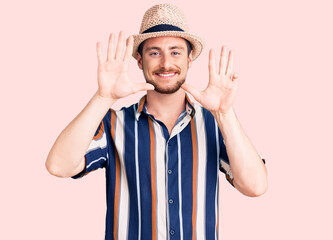 Naklejka premium Young handsome caucasian man wearing summer hat showing and pointing up with fingers number nine while smiling confident and happy.