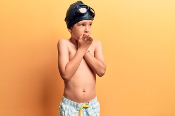 Obraz na płótnie Canvas Cute blond kid wearing swimwear and swimmer glasses looking stressed and nervous with hands on mouth biting nails. anxiety problem.