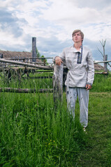 village young man stands near an old wooden fence in a field