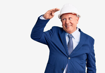 Senior handsome grey-haired man wearing suit and architect hardhat very happy and smiling looking far away with hand over head. searching concept.