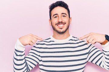 Young hispanic man wearing casual clothes looking confident with smile on face, pointing oneself with fingers proud and happy.