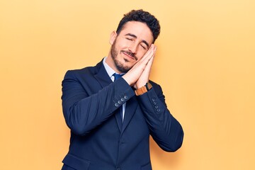 Young hispanic man wearing suit sleeping tired dreaming and posing with hands together while smiling with closed eyes.