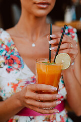 A beautiful sensual caucasian woman in a summer dress drinks juice in a cafe