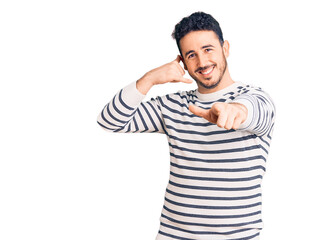 Fototapeta premium Young hispanic man wearing casual clothes smiling doing talking on the telephone gesture and pointing to you. call me.