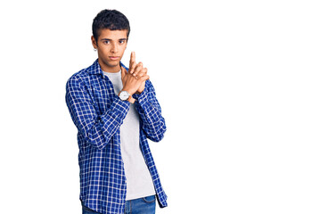 Young african amercian man wearing casual clothes holding symbolic gun with hand gesture, playing killing shooting weapons, angry face