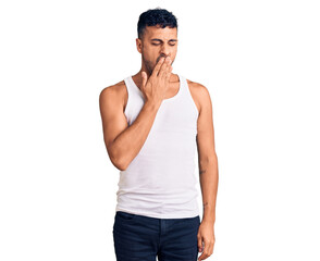 Young hispanic man wearing casual clothes bored yawning tired covering mouth with hand. restless and sleepiness.