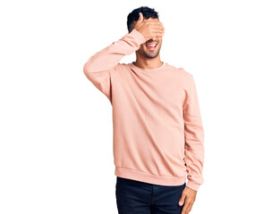 Fototapeta premium Young hispanic man wearing casual clothes smiling and laughing with hand on face covering eyes for surprise. blind concept.
