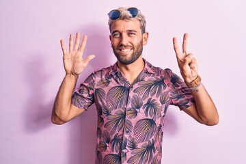 Fototapeta premium Handsome blond man on vacation wearing casual shirt and sunglasses over pink background showing and pointing up with fingers number seven while smiling confident and happy.