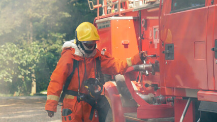 Firefighter fighting with flame using fire hose chemical water foam spray engine. Fireman wear hard...