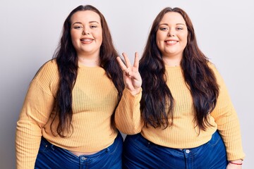 Young plus size twins wearing casual clothes showing and pointing up with fingers number three while smiling confident and happy.