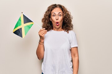 Middle age beautiful tourist woman holding italian flag over isolated white background scared and amazed with open mouth for surprise, disbelief face