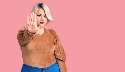 Young blonde plus size woman wearing casual sweater doing stop sing with palm of the hand. warning...