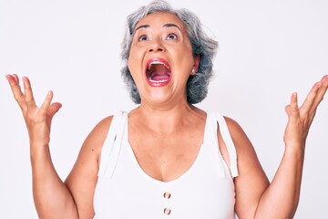 Senior hispanic woman wearing casual clothes crazy and mad shouting and yelling with aggressive expression and arms raised. frustration concept.