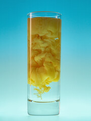 Yellow ink cloud in glass of water. Studio shot. Paint in water on blue background