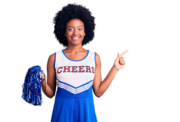 Young african american woman wearing cheerleader uniform holding pompom cheerful with a smile on...