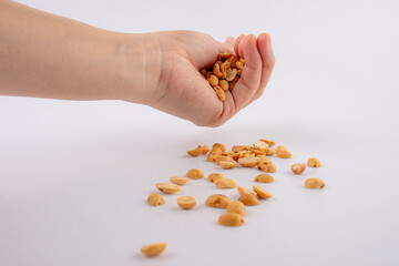 Fototapeta premium Hand holding heap of salt roasted peanuts on white background