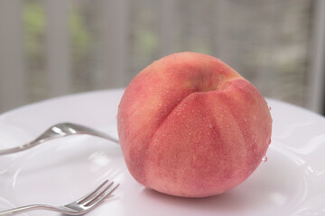 夏の果物白い皿にもられた一個の冷えた桃とフォーク