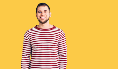 Young handsome man wearing striped sweater with a happy and cool smile on face. lucky person.