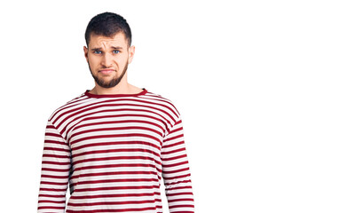 Young handsome man wearing striped sweater skeptic and nervous, frowning upset because of problem. negative person.