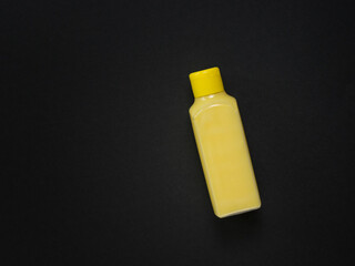 A yellow plastic bottle with a yellow liquid on a black background.