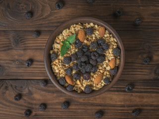Black raspberries scattered on the table and a bowl of granola.