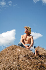 young guy in a cowboy hat is sunbathing on a haystack