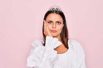 Young beautiful brunette woman wearing princess tiara standing over isolated pink background thinking looking tired and bored with depression problems with crossed arms. © Krakenimages.com