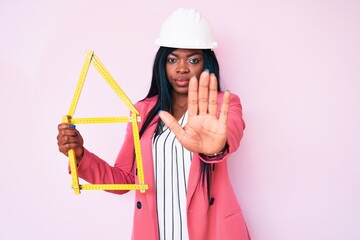 Young african american woman wearing bike helmet and holding water bottle with open hand doing stop sign with serious and confident expression, defense gesture