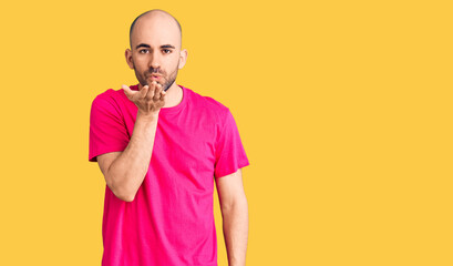 Young handsome man wearing casual t shirt looking at the camera blowing a kiss with hand on air being lovely and sexy. love expression.