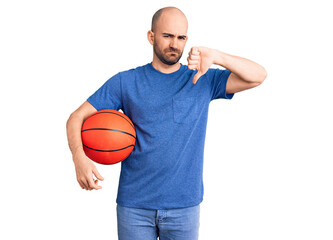 Young handsome man holding basketball ball with angry face, negative sign showing dislike with thumbs down, rejection concept