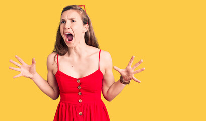 Young beautiful blonde woman wearing casual dress crazy and mad shouting and yelling with aggressive expression and arms raised. frustration concept.