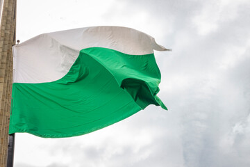 Flag of Antioquia waving in a blue cloudy sky