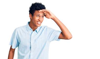 Young african american man wearing casual clothes very happy and smiling looking far away with hand over head. searching concept.