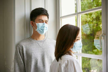 young asian couple wearing mask staying at home