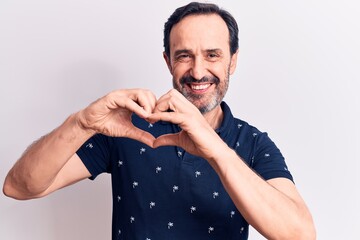 Middle age handsome man wearing casual polo standing over isolated white background smiling in love doing heart symbol shape with hands. Romantic concept.