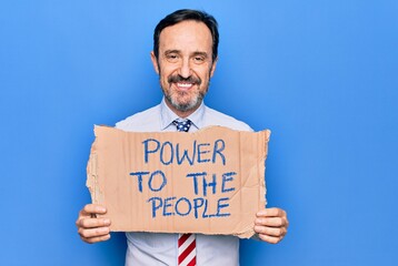 Middle age business man wearing usa tie holding banner with power to the people message looking positive and happy standing and smiling with a confident smile showing teeth