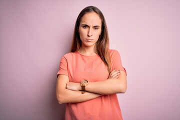 Obraz premium Young beautiful woman wearing casual t-shirt standing over isolated pink background skeptic and nervous, disapproving expression on face with crossed arms. Negative person.