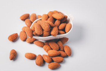 Almonds in a white ceramic cup on a white background
